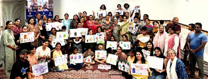 Caregivers and children at a Stronger Together session holding their artwork